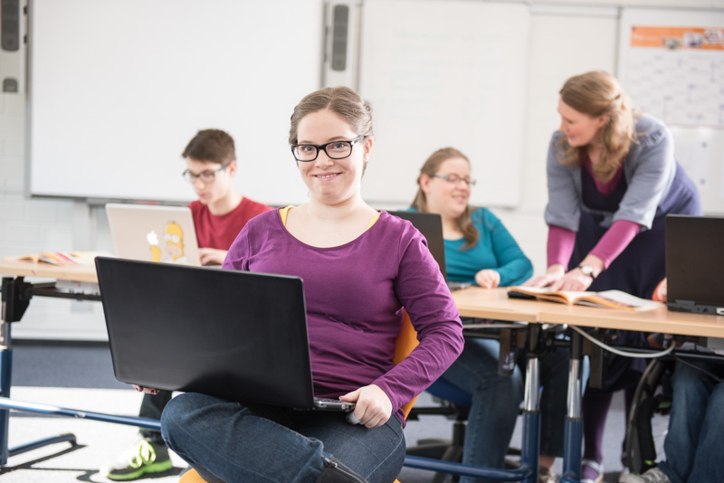 Schülerin mit einem Laptop auf dem Schoß.