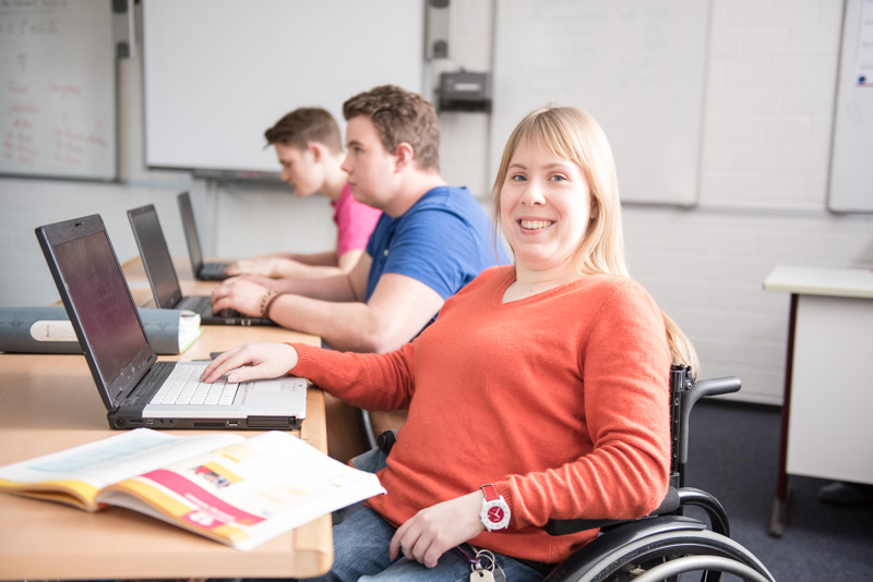 Drei Schüler:innen sitzen nebeneinander an ihren Computern.