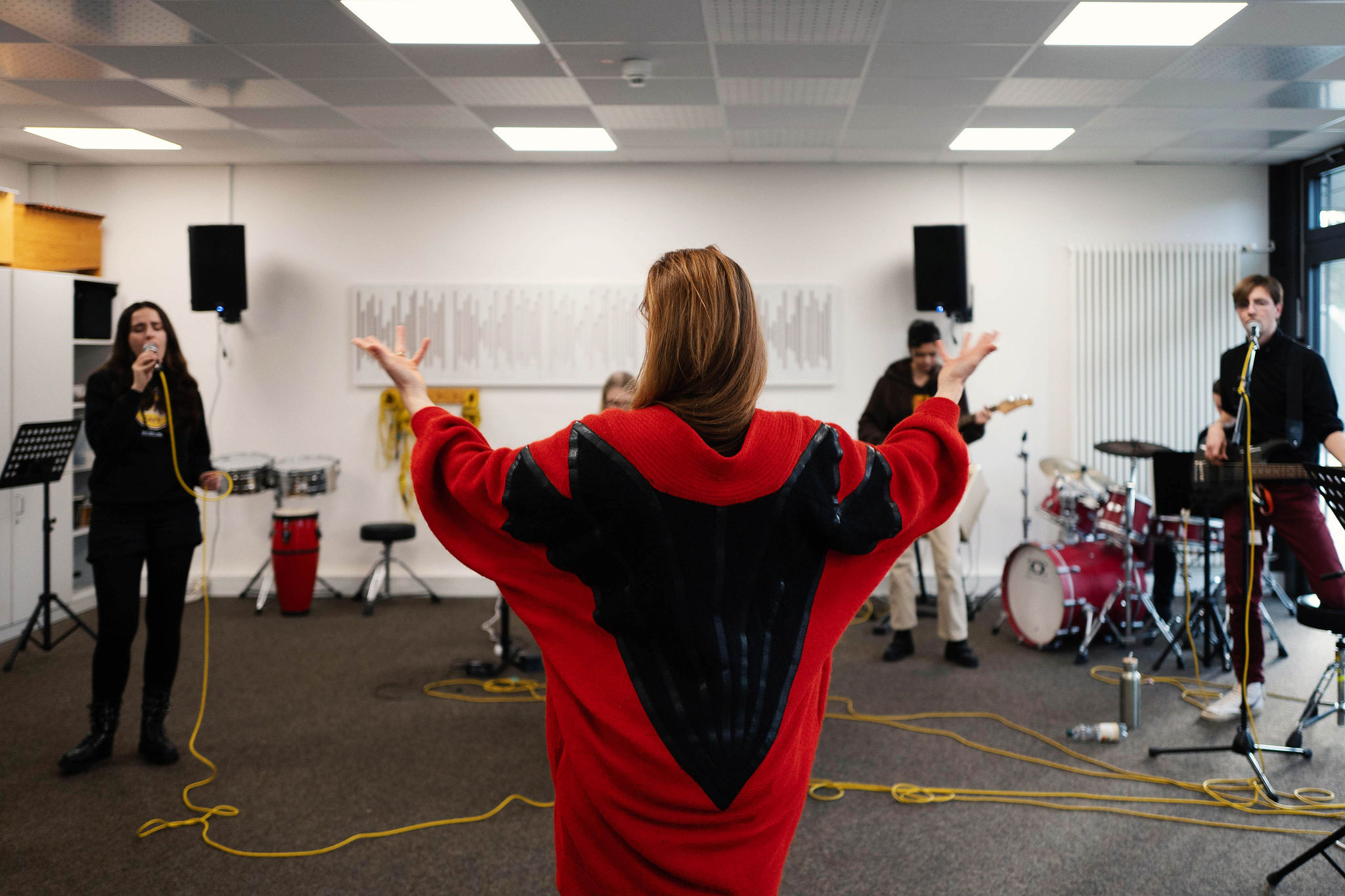 Jurorin Stephanie Neigel beim Coaching (SRH School Band Award 2024); im Hintergrund ist eine teilnehmende Schulband zu sehen