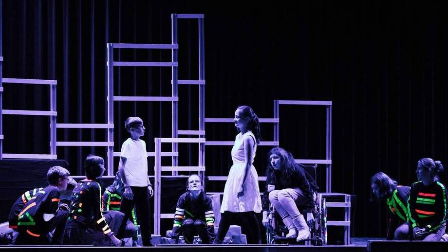 Szene des Musiktheaters KUPFER zeigt dunkle Kulisse mit Neonlichtern und den beiden Protagonisten im Vordergrund auf der Bühne.