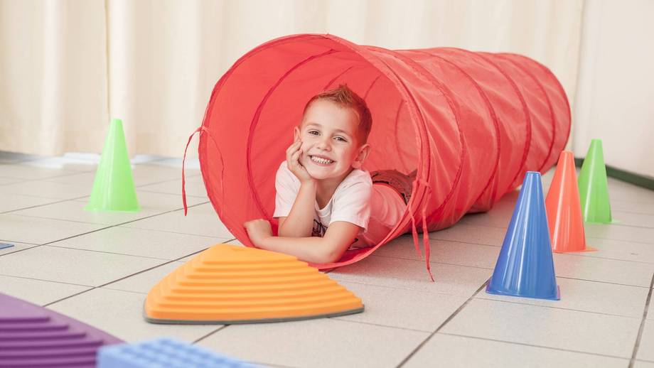 Schüler liegt am Ausgang eines Krabbeltunnels und stützt den Kopf auf der Handfläche ab.