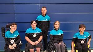 Teamfoto des Rollstuhltischtennisteams am 1. Spieltag der Regionalliga. Vier Spieler:innen vorne im Bild; der Trainer im Hintergrund