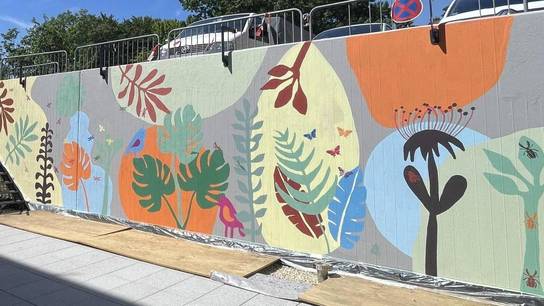 Die einst einfarbige Mauer wurde von den Schüler:innen mit einem floralen Wandbild, welches an eine Blumenwiese erinnert, verschönert.