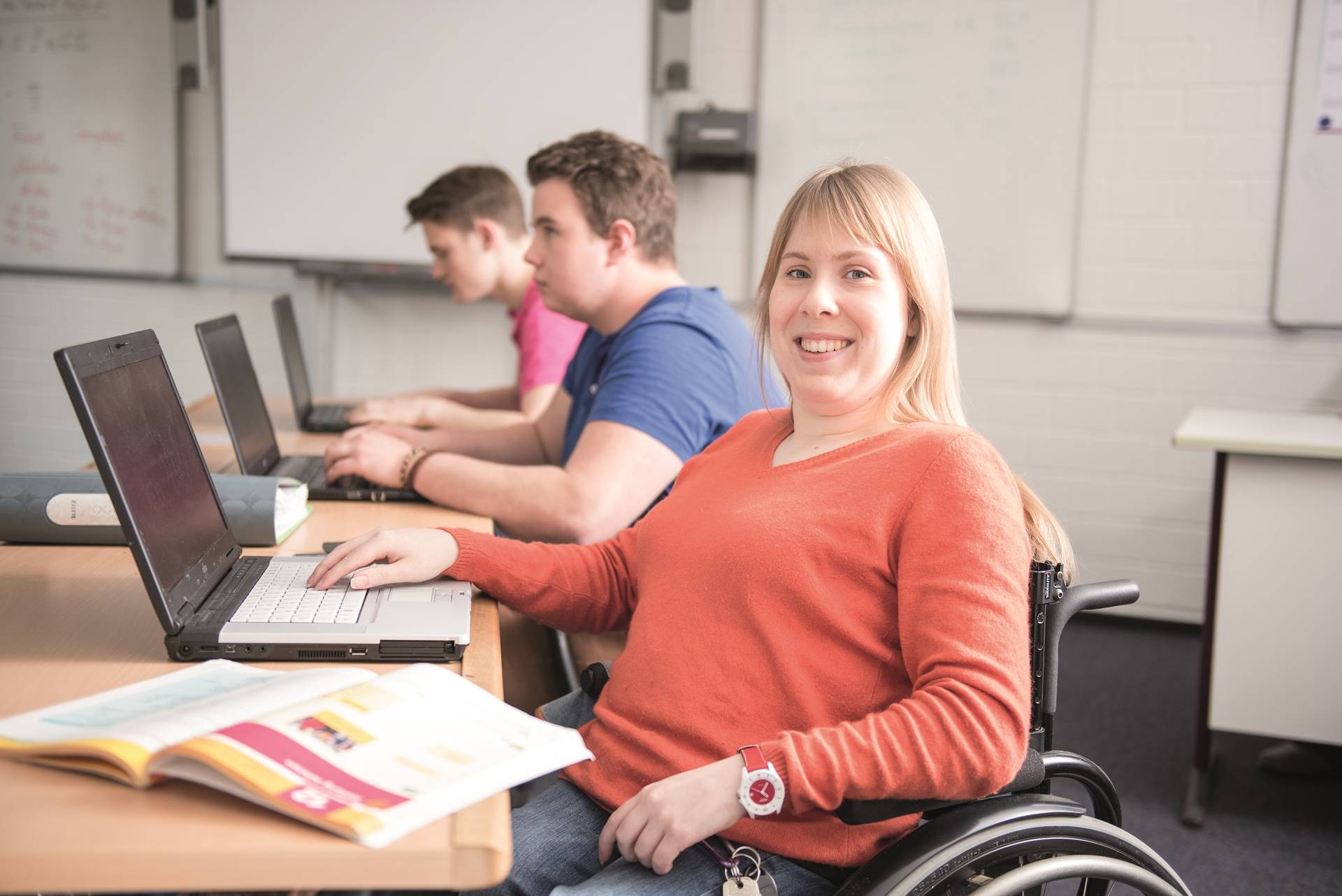 Drei Schüler:innen sitzen nebeneinander an ihren Computern.