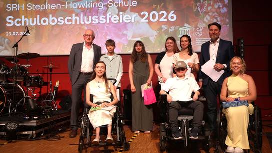 Gruppenbild der stolzen Preisträger:innen des SRH Leistungspreises + Geschäftsführer und Schulleiter auf der Bühne.