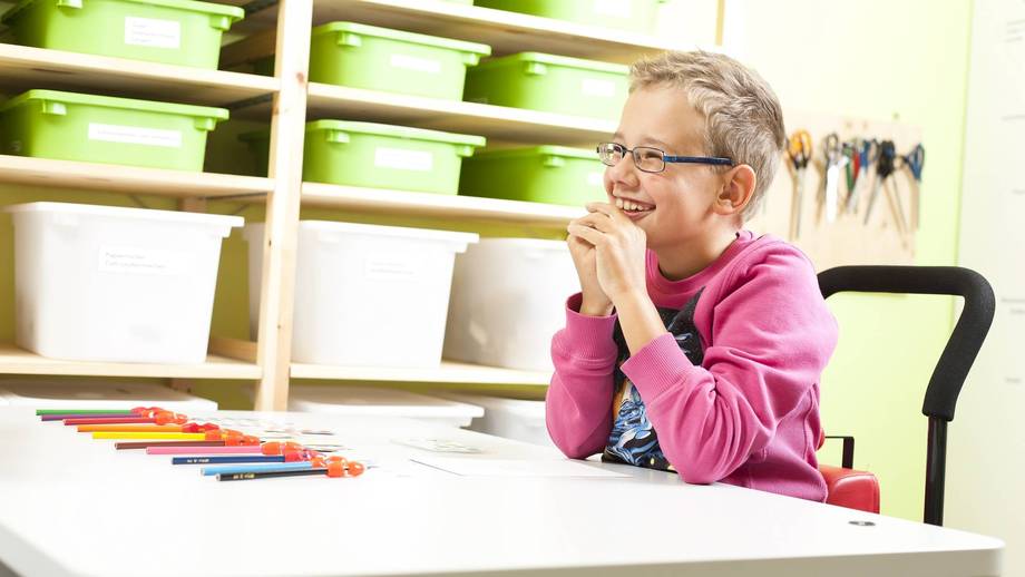 Vor dem Schüler liegen Stifte mit Schreibhilfen.