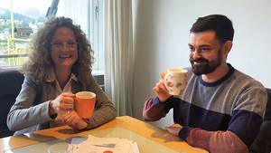 Jutta, die Nachhaltigkeitsbeauftragte der SRH Schulen, spricht mit ihrem Kollegen über die Nachhaltigkeit im Internat der SRH SHS. Beide sitzen am Tisch und trinken gemeinsam je ein Heißgetränk.