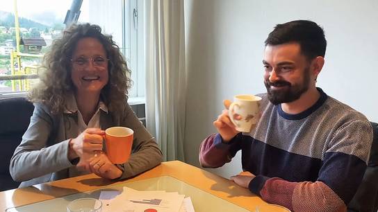 Jutta, die Nachhaltigkeitsbeauftragte der SRH Schulen, spricht mit ihrem Kollegen über die Nachhaltigkeit im Internat der SRH SHS. Beide sitzen am Tisch und trinken gemeinsam je ein Heißgetränk.