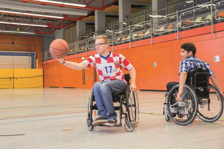 Zwei Schüler spielen in der Turnhalle Rollstuhl-Basketball.