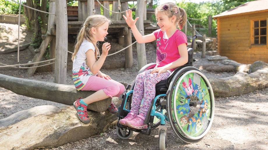 Zwei Mädchen geben sich High Five im naturnahen Pausenbereich des Primargeländes.