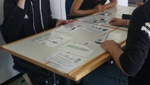 Schüler:innen sitzen am Tisch und spielen ein thematisch passendes Memory.