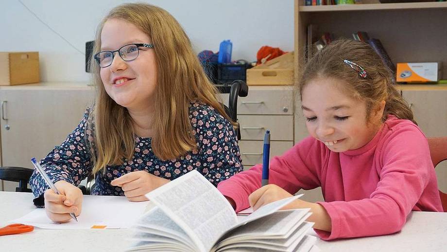 Internatsschülerin Kimberly sitzt neben ihrer Mitschülerin an der Schulbank.