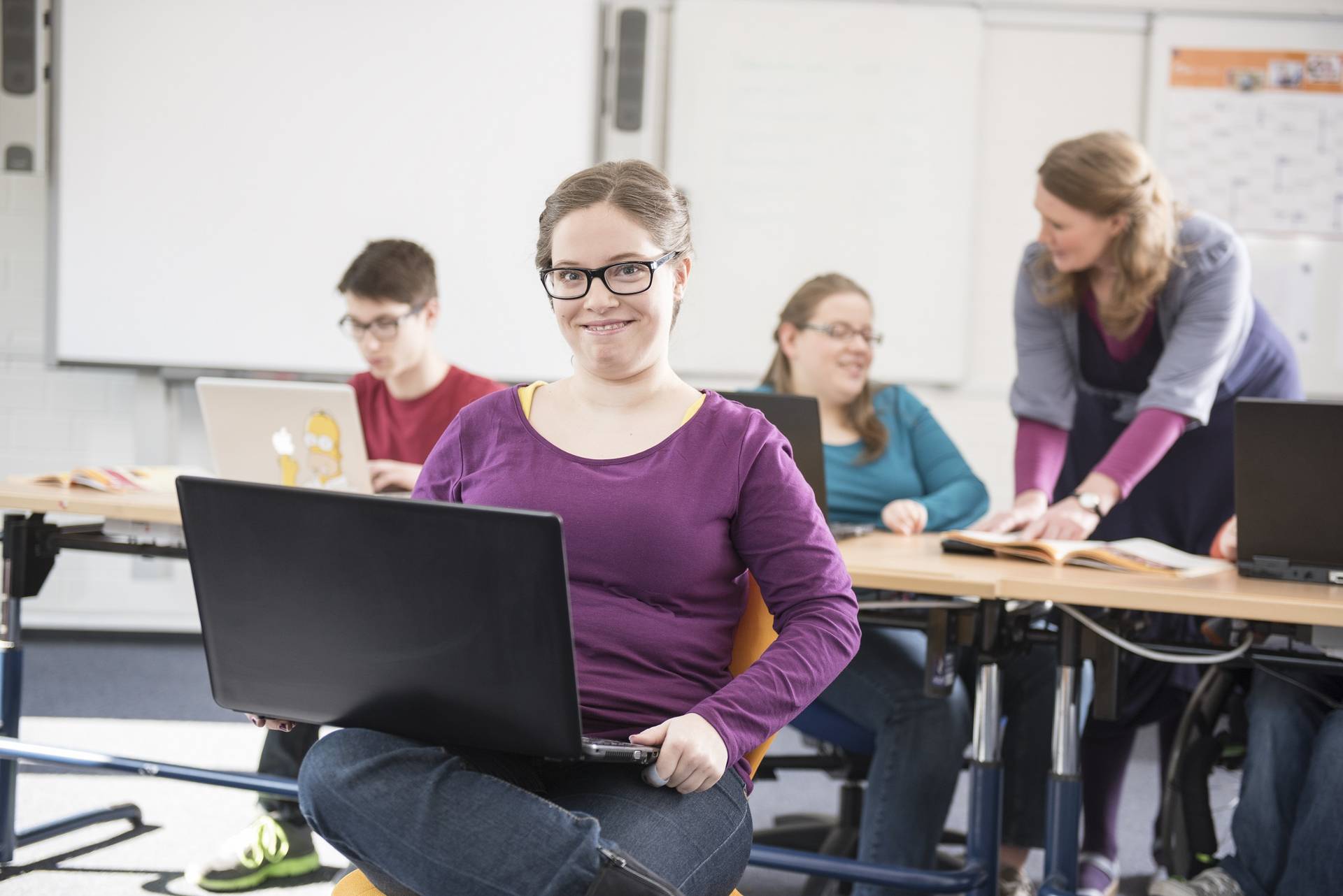 Schülerin mit einem Laptop auf dem Schoß.