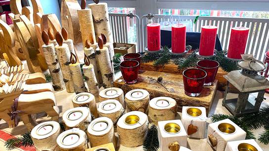 Verkaufsstand mit zahlreichen Kerzen und Holzdekorationen des Weihnachtsbasars des SRH Bildungscampus Neckargemünd.