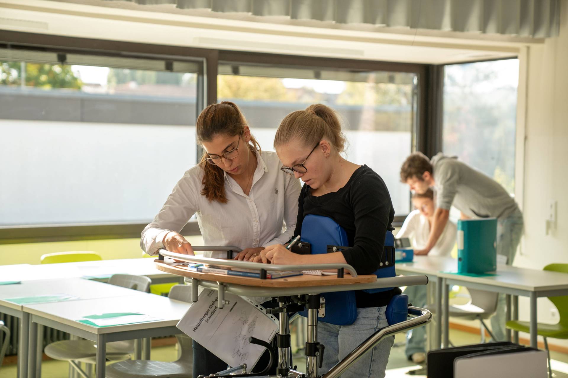 Schülerinnen und Lehrkräfte befinden sich in Zweier-Teamarbeit im Klassenzimmer.
