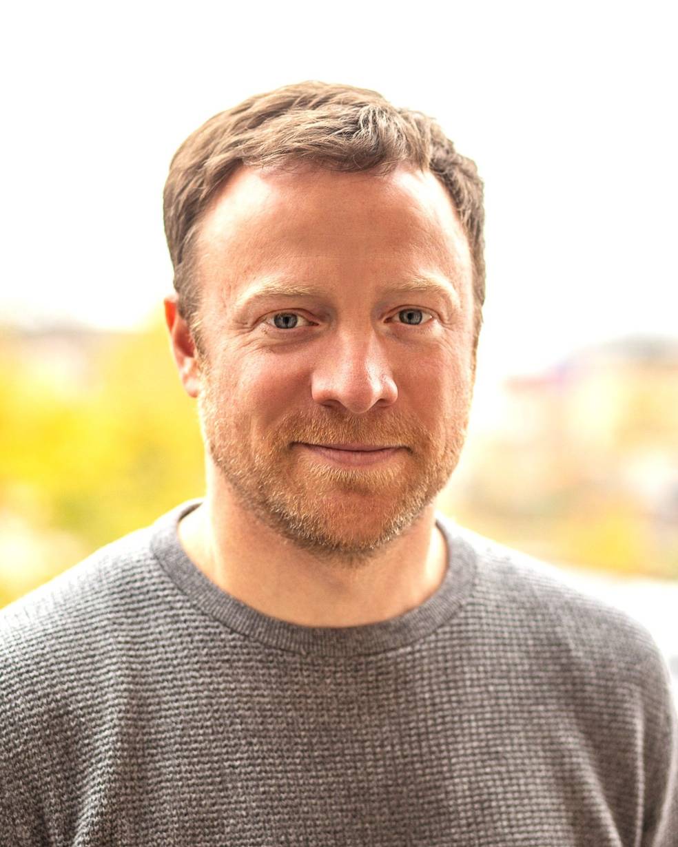 Freundliches Portrait des Juroren Sören Gerhold. Im Hintergrund befindet sich eine verschwommene Landschaft.