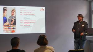 Die schulische Abteilungsleitung begrüßt die Gäste und stellt den Tagesablauf dar.