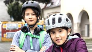 Ein Mädchen und ein Junge mit Helm auf dem Fahrrad