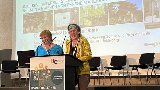 Dr. Regine Oberle und Claudia Hanko am Rednerpult im Rahmen der Kooperation zum barrierearmen Pilgerweg Camino Incluso