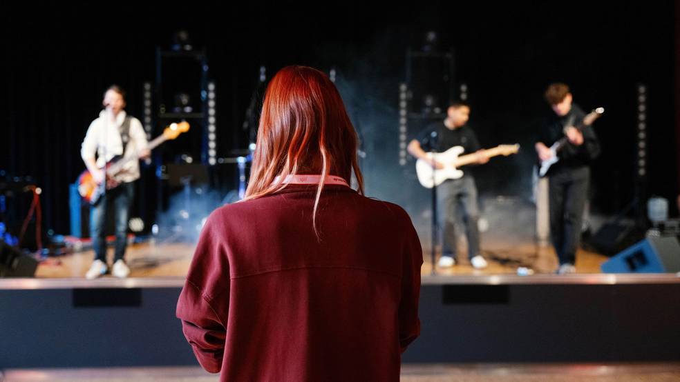 Im Vordergrund steht Jurorin Alex Mayr beim Coaching (SRH School Band Award 2024); im Hintergrund ist eine Teilnehmerband zu sehen